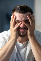 jeune homme se cachant le visage avec ses mains avec les yeux visibles avec le sourire