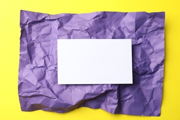 Blank card and crumpled paper on yellow background, top view