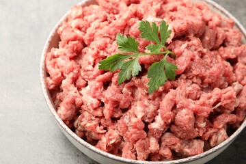 Raw minced meat with parsley on grey table, closeup