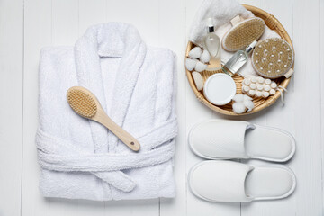 Flat lay composition with bathrobe and spa essentials on white wooden background