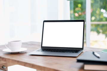Fototapeta premium Laptop with empty white screen and stationery on desk in room. Comfortable home workplace
