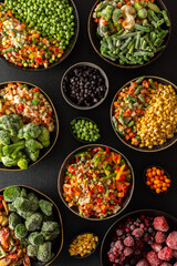 Fresh fruits and vegetables, frozen and placed in plates, on a dark backdrop, symbolizing the process of summer preparations for the colder months ahead