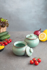 Ceramic baking pots on the table among vegetables and herbs