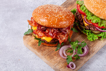 two burgers with beef patty, fried bacon, cheddar cheese, tomatoes, homemade, no people,