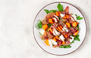 salad with slices of ripe melon, prosciutto, mozzarella and fresh arugula, decorated with balsamic glaze.
