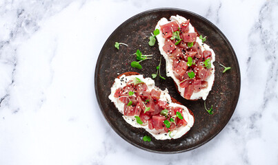 sandwiches, rye bread with cream cheese, sliced tuna fillet with herbs, breakfast on a black plate, homemade,