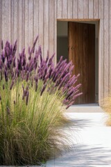 At the entrance of a contemporary home, vibrant purple grass beautifully contrasts with the elegant wooden architecture, all set against a backdrop of lush natural landscaping.