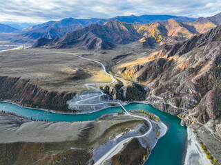Aerial perspective showcasing a hairpin turn on a road and the confluence of river sections amidst...