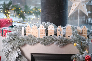 Christmas Mantlepiece Decoration with Small Wooden Houses and Frosted Pine Garland. Cozy Winter Village