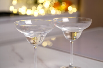 Two Empty Cocktail Glasses on a Marble Surface with Golden Bokeh Lights Background
