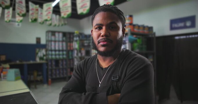 Confident young man standing with arms crossed in a paint store, representing professionalism, leadership, and a strong work ethic in a retail environment