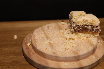 A piece of cornstarch alfajor on a wooden tray photographed up close
