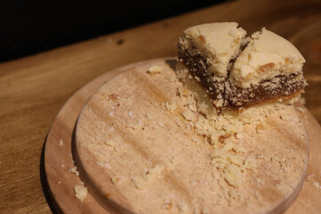 A piece of cornstarch alfajor on a wooden tray photographed from top to bottom