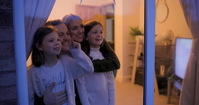 Happy family at home looking out of the window at night and having fun