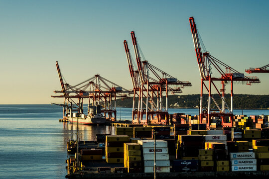 Halifax, NS - CA - Sep 29, 2025 A cargo ship is docked at the Port of Halifax, Canada, with multiple red and white gantry cranes and stacks of containers.