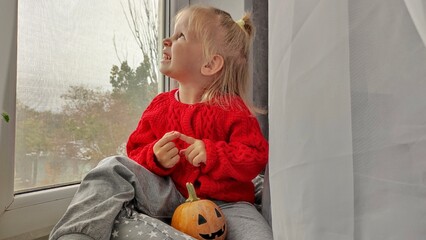 A little girl holds a pumpkin on Halloween, preparing for the celebration