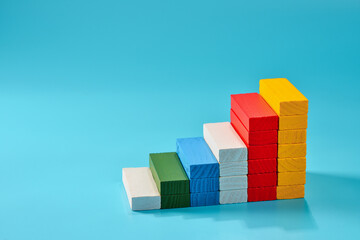 Colorful wooden blocks create a staircase pattern on a blue background showcasing creativity and learning in educational playtime, copy space.