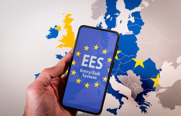 Hand holding a smartphone displaying the European Union EES EntryExit System on screen, symbolizing...