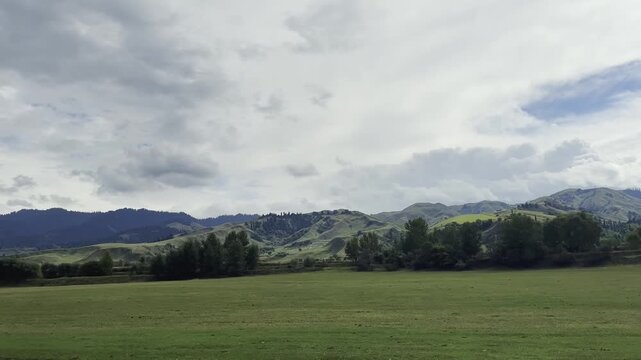 mountain and grassland under cloudy sky as seen from a traveling vehicle, xinjiang, china