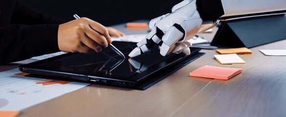 A robot arm interacts with a human hand on a tablet, showcasing a collaborative effort in a modern...
