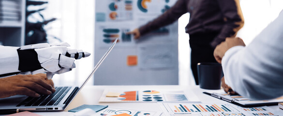 A modern office scene showcasing a robotic arm engaged in a business meeting, analyzing data and collaborating with human team members in a professional environment.Noogenesis