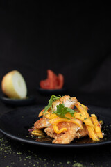Elegant plate of fried chicken strips with mango and parsley garnish.