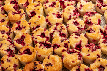 Rows of golden brown raspberry rolls cool on a tray, showcasing their sweet and fruity filling
