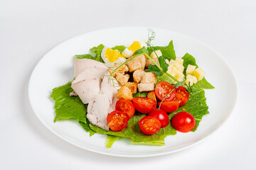 Vibrant salad with greens, cherry tomatoes, sliced chicken, and croutons is beautifully plated