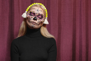 Portrait of a model wearing elaborate sugar-skull makeup and headscarf with ornate floral detailing, bold colors creating Day of the Dead cultural and editorial aesthetic