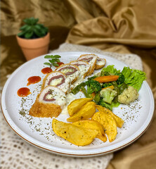 Delicious cordon bleu dish with potatoes and vegetables on a plate.