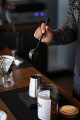 Barista preparing coffee with a spoon and coffee beans.