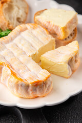 Washed rind cheese soft cheese with orange rind munster french cheese tasty snack fresh delicious gourmet food background on the table rustic top view copy space