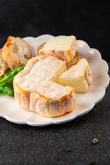 Washed rind cheese soft cheese with orange rind munster french cheese tasty snack fresh delicious gourmet food background on the table rustic top view copy space