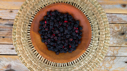 Wooden bowl with fresh blackberries on rustic table