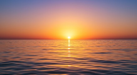 Fototapeta premium Ocean sunset horizon scene with vibrant orange and yellow colors reflecting on calm water