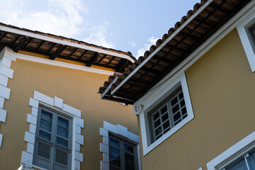Yellow Building Corner With White Trim And Tile Roofs, Colonial Style Architecture
