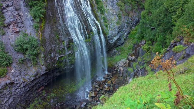 A scenic view of the beautiful Narada Falls cascading through a vibrant green forest at Mount Rainier National Park