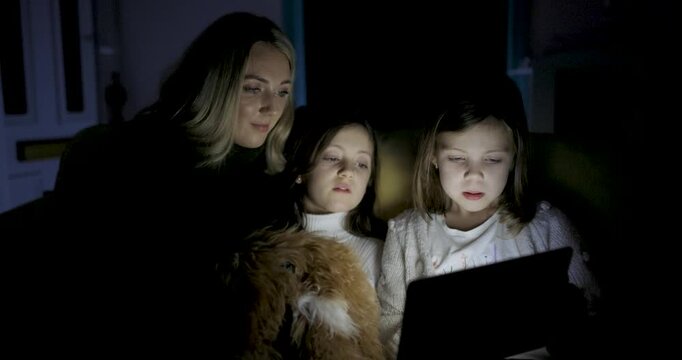 Woman and two girls using digital tablet at home to read ebook and remote learning