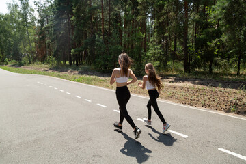 Fototapeta premium Happy active mother and child jogging outdoors, running in forest