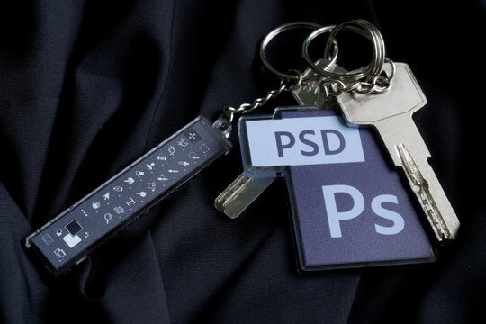 House keys with Adobe Photoshop PSD and toolbar keychains on dark cloth, symbol of efficient photo editing workflow. Photo. Barcelona, Spain, October 10, 2025