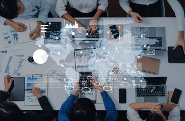A group of business professionals engage in a data analysis session with laptops and charts in a modern office, featuring a global map overlay for visualization. Trope