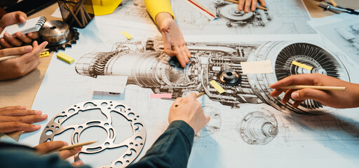 A diverse group of hands engaged in a collaborative engineering project, analyzing technical...