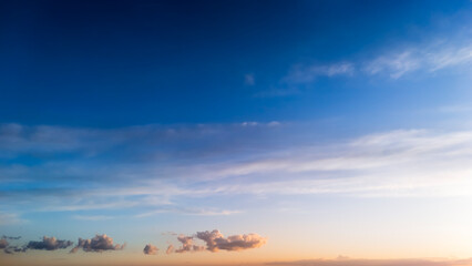Obraz premium A panoramic view of a clear blue sky with soft clouds, capturing the serene transition from day to dusk. Ideal for nature and landscape themes in various media.