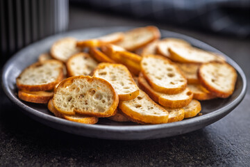 Crispy roasted bruschetta bread on plate on black table.
