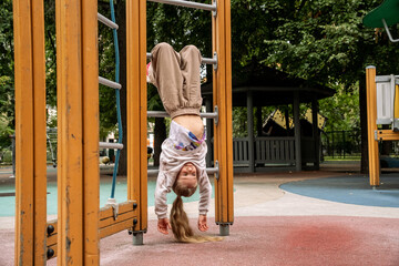 Young Girl Hanging Upside Down at Playground
