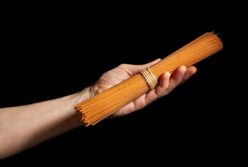 brown integrale spaghetti in hand isolated on black