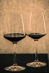 A minimalist studio shot of two elegant red wine glasses on a dark, moody background, conveying luxury.