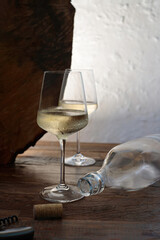 An artistic still life of a glass of white wine with a dramatic play of light and shadow from a natural object.