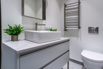 Bright bathroom showcases a minimalist design with a modern square sink, chic cabinet, and green plants. The clean lines create a fresh and calming atmosphere