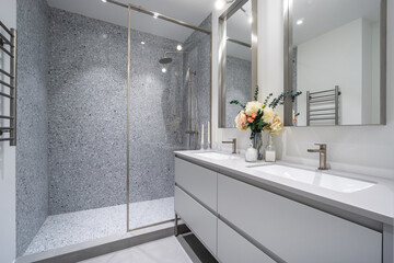 A modern bathroom showcases a sleek design with a spacious glass shower, double sinks, and fresh...